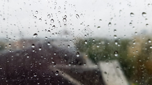 在多云的天气里 秋天的城市背景上滴着湿窗户 雨中窗外景色 雨中玻璃窗上的水滴 城市场景背景模糊玻璃气泡街道下雨建筑物秋雨景观戏剧图片