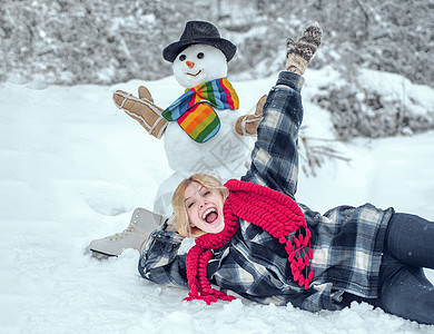 雪人和滑稽的女模 穿着冬帽 戴着红鼻子围巾 在雪地村落打雪可爱的人 (笑声)图片