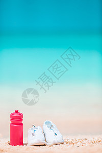 白沙沙滩上的运动鞋和酒瓶支撑娱乐闲暇阳光热带旅行橡皮衣服海浪旅游图片