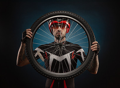 戴自行车头盔和自行车车轮的男运动员衣服竞赛维修配件齿轮赛车手成人微笑店铺辐条图片