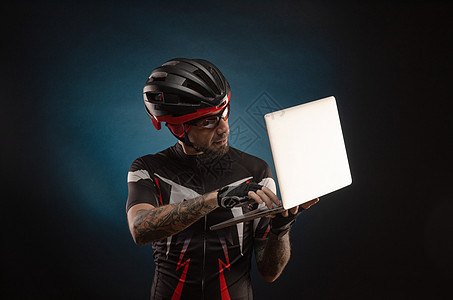 用笔记本电脑戴自行车头盔的男运动员男人配件展示微笑齿轮眼镜成人销售量竞赛学习图片