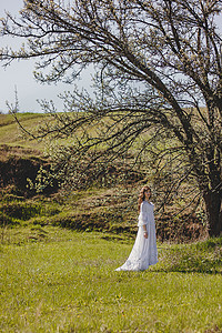 在春樱花花花园山谷穿着白年式婚纱的无忧无虑年轻女子的肖像幸福自由花朵新娘黑发裙子成人快乐公园头发图片