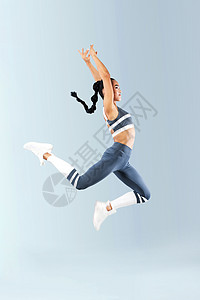 穿着运动服跳跃快乐的喜悦 在灰色背景上孤立一触即发运动损失活力女性幸福技术运动员训练工作室舞蹈家图片