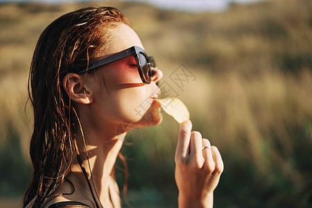 在自然阳光下吃薯片的太阳镜上小吃芯片饮食食物青少年筹码微笑乐趣垃圾成人图片