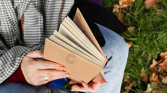 在秋天的公园里读书的女孩 在温暖的阳光明媚的日子里 女性的手在户外打开纸质书的页面 学生正在准备考试 文艺休闲自然文学小说森林叶背景图片