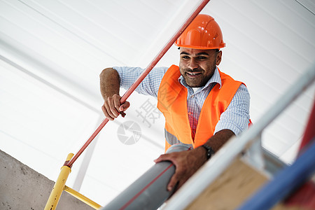 在建筑工地架脚手架上攀爬的年轻英俊建筑工人讲师建造开发工具职业结构领班男性建筑师标志图片
