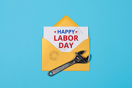 劳动节快乐的概念 黄色信封和蓝色背景的扳手作坊金属硬件工作工具机械工程维修劳动黑板图片