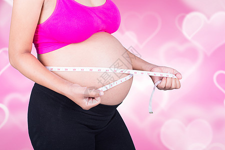 孕妇的近身腹部 心脏背景有测量胶带图片