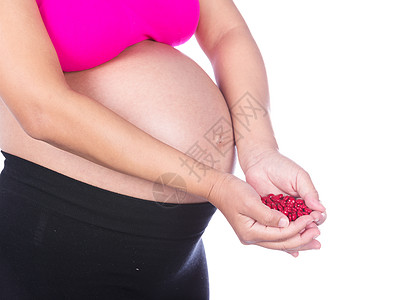 怀着白色背景 手上拿着红色药丸的孕妇女士卫生生活身体母亲疾病维生素药片腹部药品图片