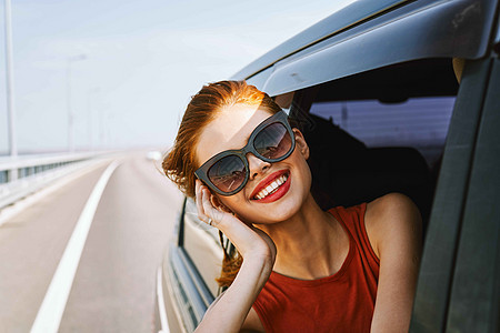 戴太阳眼镜的漂亮女人骑着旅行车汽车潮人假期车辆晴天游客旅行窗户太阳镜女孩图片