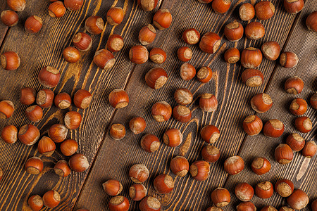 许多带壳的榛子均匀地分布在棕色的木质表面上桌子宏观坚果地面饮食核心贝壳团体墙纸营养图片