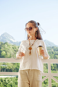 美丽的女人在山前的阳台上 喝着咖啡躺着休息图片