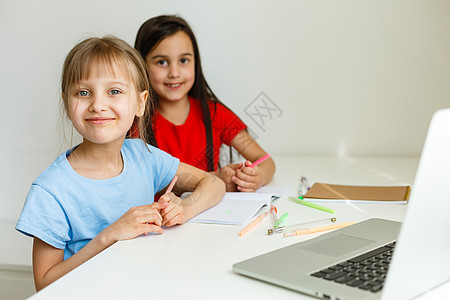 两个女孩 最年长和最小的女孩 在笔记本电脑上的一张桌子上订婚童年妻子教育互联网家庭技术学校孩子学习女学生图片