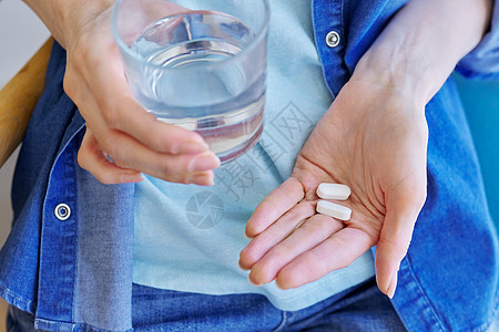 用药丸和水杯把成年女性的手拉近剂量疼痛接待抗生素化学卫生疾病玻璃保健食物图片