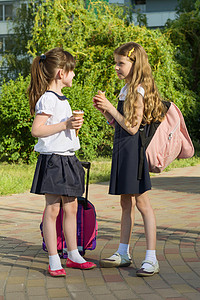 看见两个女学生女友背着背包 吃冰淇淋的背包童年女孩们城市教育快乐幸福头发街道学生孩子图片