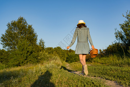 有个女孩在乡间公路上 背面看到一个女孩的外出画像了 她有篮子草莓和草帽图片