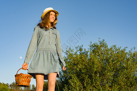 青少年女孩室外夏天画象有篮子草莓的 草帽 自然背景 乡村景观 绿色草地 乡村风格图片