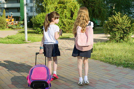 两个女学生女朋友小学生在院子里背着书包走路的后视图图片