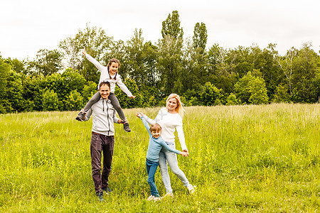 家庭快乐 在户外草地享受生活阳光闲暇父亲跑步母亲父母孩子太阳儿子喜悦图片