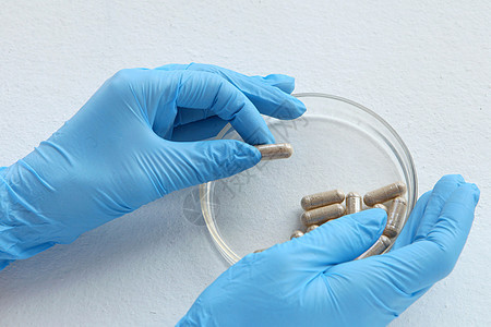 蓝色发光的化学家在实验室 用玻璃板测试 实验室玻璃上的有机药丸用于医学测试 从姜的草本胶囊在白色背景生态帮助药品治疗植物药剂草本图片