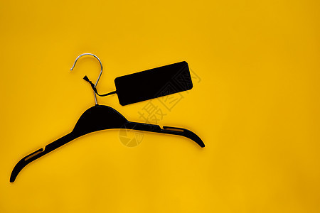 黑色衣架与黑色纸标签隔离在黄色纸背景上 服装标签 标签空白样机模板 用于放置您的设计 黑色星期五最终销售横幅图片