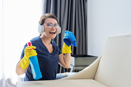 妇女做家庭清洁 耳机和洗涤剂手套上的女性家具家务桌子主妇房间家政清洁工打扫成人皮革图片