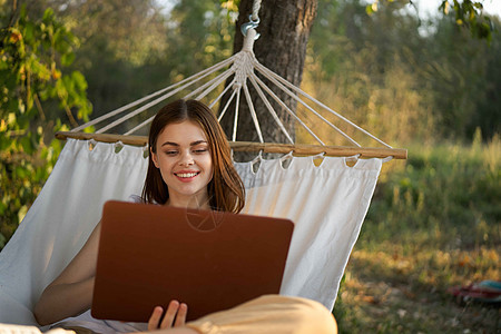 妇女用笔记本电脑 睡在吊床上自然度假自由职业者互联网海滩丛林公园阅读旅行享受热带假期女孩图片