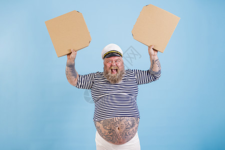 身着水手服装超重的喜悦男人 拿着白披萨盒 在浅蓝色背景上图片