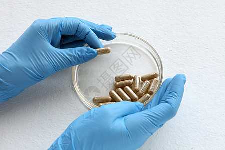 蓝色发光的化学家在实验室 用玻璃板测试 实验室玻璃上的有机药丸用于医学测试 从姜的草本胶囊在白色背景草本植物治疗药店疾病药物止痛图片