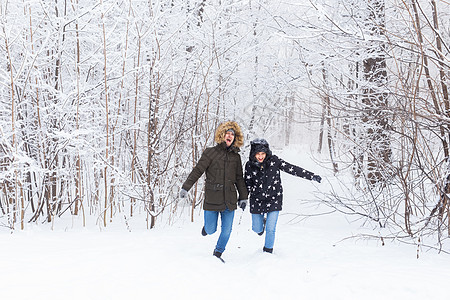 冬天快乐的一对情侣在雪雨林中走过寒冬天气太阳乐趣幸福女性照片成人夫妻闲暇森林图片