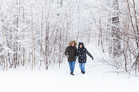 冬天快乐的一对情侣在雪雨林中走过寒冬男人树木太阳闲暇幸福天气季节阳光照片感情图片