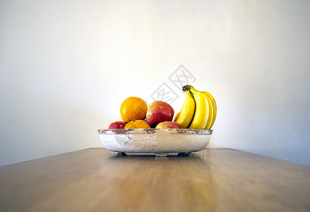 木桌上健康的新鲜水果碗 香蕉 橙子和苹果靠近白墙 木桌上的现代设计 复制空间健康的静物生活前景图片