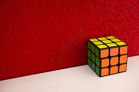 在红色墙壁附近的白色木架子上解决拼图速度立方体彩色魔方与复制空间思维挑战骰子娱乐积木社论压力正方形数学思考智力游戏图片