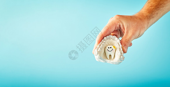 男性在蓝背景上持有牙齿 看牙医 口腔病广告概念 牙科健康 请访问医生办公室InfoFinland支撑蓝色保健药品塑料男人技术医学图片