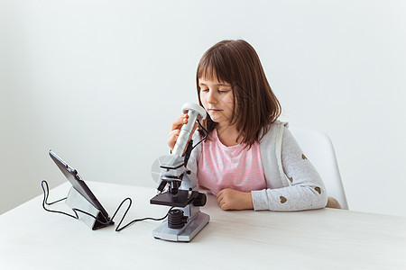 在科学课中使用显微镜的女学生 技术 课程和儿童概念生物学知识桌子黑色学习课堂教育科学家乐器检查背景图片