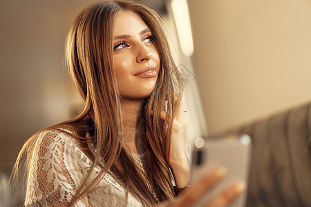 快乐的年轻女士坐在自助餐厅时使用智能手机微笑成人技术店铺大学食堂电话商务餐厅女性图片
