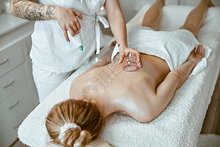 专业女性专家 在美丽的caucasian女士的背上 正在做结衣疗法治疗师玻璃疼痛针刺技术工作愈合职业按摩八关图片