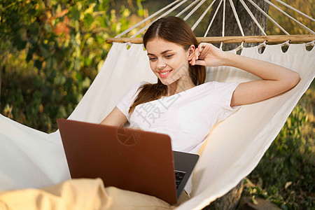 妇女在自然度假旅行中热爱膝上型电脑享受阅读屏幕海滩女士女孩吊床公园女性丛林图片