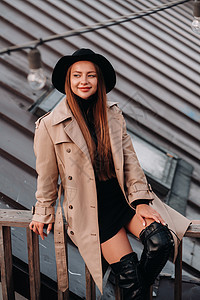 穿着美衣和黑帽子的时髦年轻女子坐在市中心的屋顶上 妇女街道潮流 秋季服装 城市风格成人奢华太阳镜春装时尚皮革配件外套魅力帽子图片