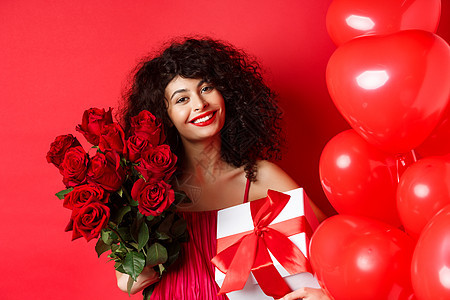 浪漫女性在节假日接受花束和礼物 站在心脏气球和红色背景的旁边 微笑着感激之情周年卷曲情感女朋友伙伴投标盒子男朋友裙子女士图片