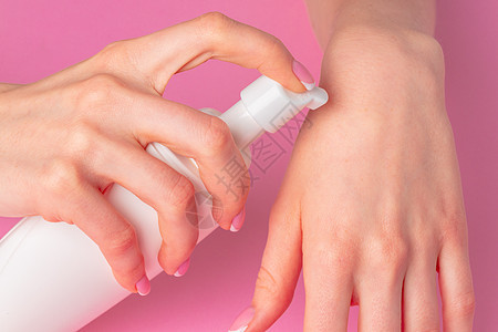 女性手持粉红色的皮肤护理产品瓶洗发水手指润肤卫生女孩产品手腕化妆品瓶子温泉图片