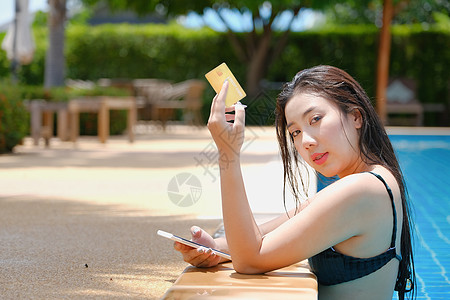 在线支付 一位会游泳的少女正在使用她的信用卡和她的手机进行购买 通过互联网在线信用电话店铺女士购物技术金融命令风险男人图片