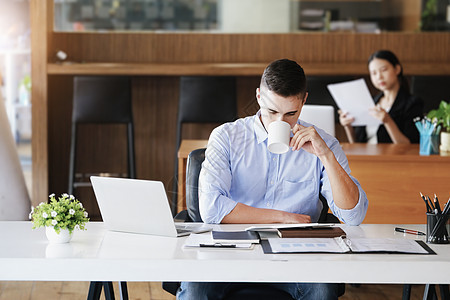 在使用电脑 iPad 和营销分析文件之前 男性营销经理一边工作一边喝咖啡以减少睡意办公室咨询女士协议经济簿记检查审计商务计算器图片