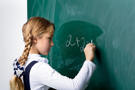 课堂上在黑板上写字的女学生女性背包童年孩子们瞳孔智力照片学生知识粉笔图片
