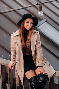 穿着美衣和黑帽子的时髦年轻女子坐在市中心的屋顶上 妇女街道潮流 秋季服装 城市风格帽子围巾奢华配件皮革成人时尚外套魅力女孩图片