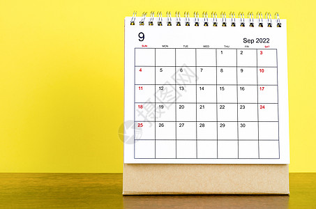 9月2022日 桌边有黄色背景的表格日历 在木制桌子上图片