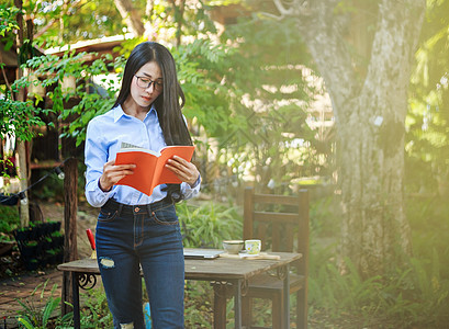 在花园里看书的女人肖像衬衫学生微笑阅读知识女性女孩闲暇学校眼镜图片