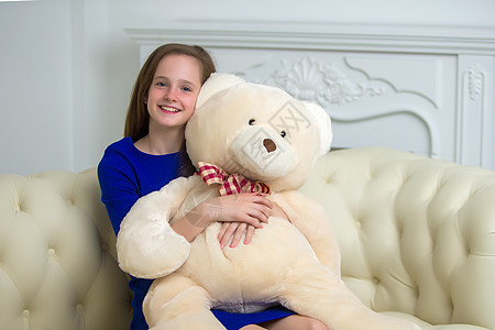 美丽的十几岁学龄少女坐在沙发上 带着泰迪熊坐着女性父母童年喜悦枕头女儿快乐女士家庭长椅图片
