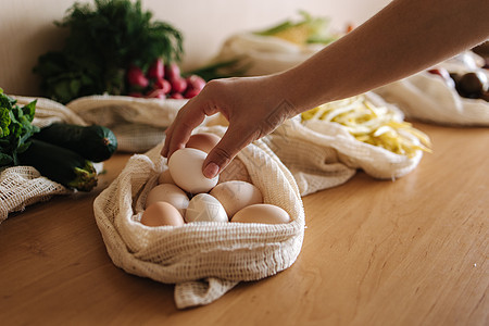 女性用手从纸布杂货袋中取鸡蛋 木制桌上可再使用生态棉袋中的蔬菜 零废物购物概念工艺浪费营养市场厨房杂货店烹饪水果店铺香菜图片