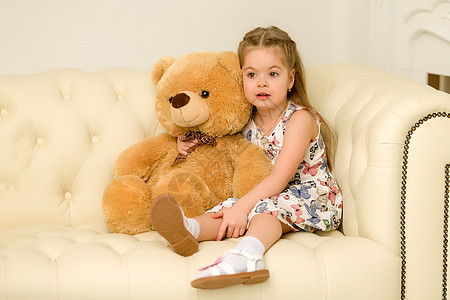 抱着泰迪熊的沙发小女孩喜悦婴儿女儿拥抱玩具幸福女孩女士乐趣快乐图片